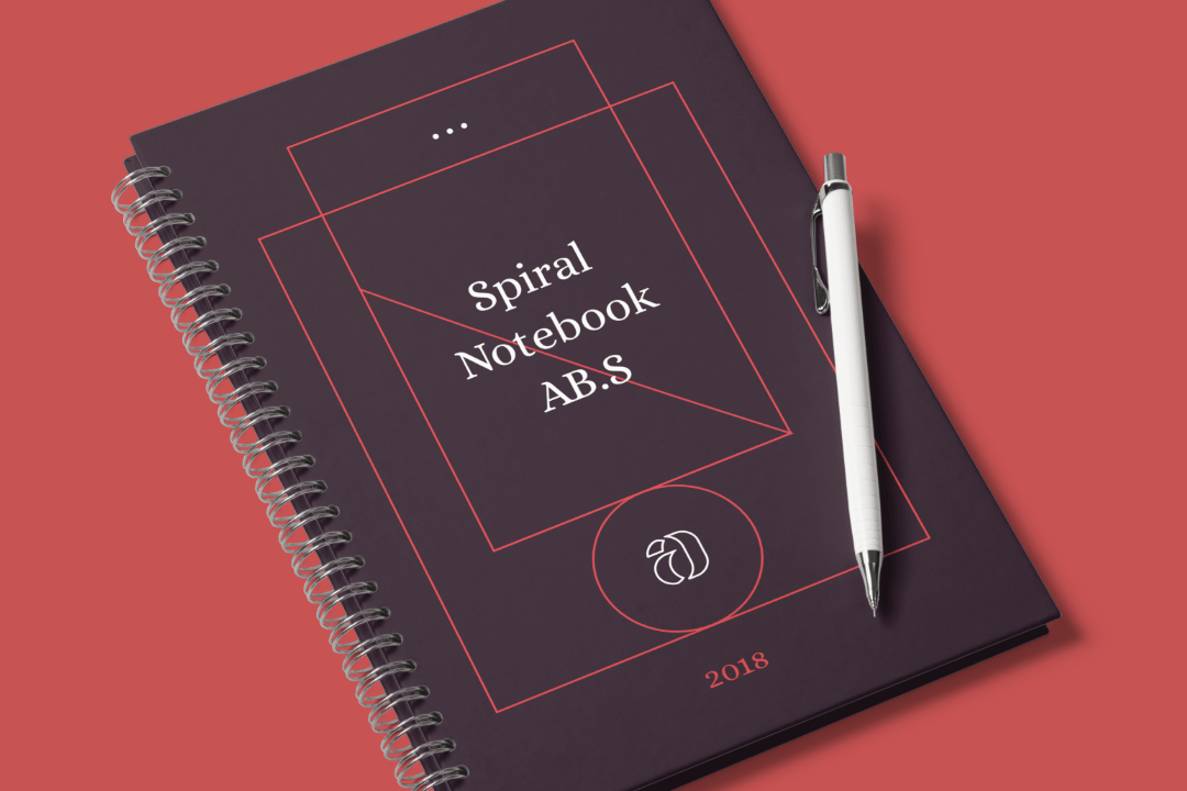 A portrait bound book standing on a white . Spiral Notebook Mockup Scene